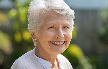 An elderly smiling woman outdooors