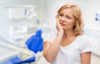 A concerned woman with dental issue at a dentist office.