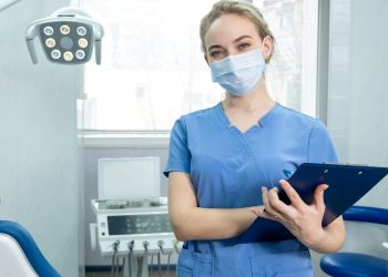 A female dental care professional wearing a surgical mask in a dental treatment room., Indian Land, SC