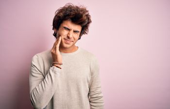 Young man with thick wavy hair suffering from jaw pain., Indian Land, SC